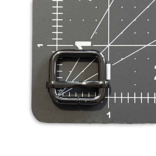 Gunmetal slide adjuster shown on a cutting mat for scale.